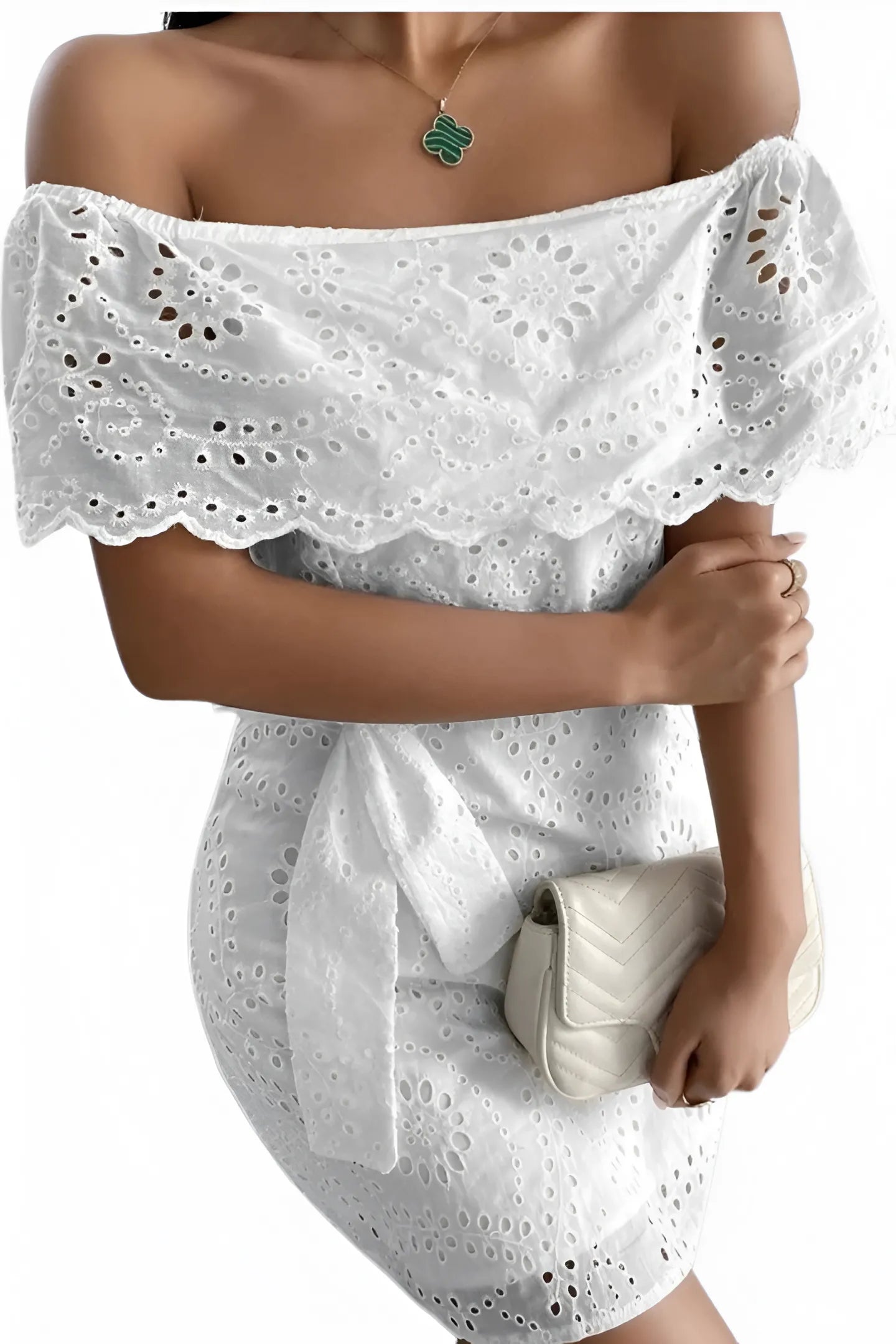 Gros plan sur une robe blanche bohème à col Bardot, mettant en valeur son grand volant en broderie anglaise.